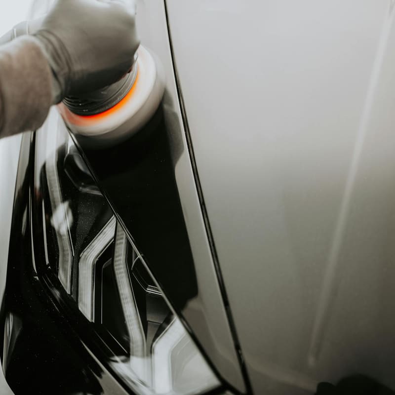 Dual-action polisher on a glossy black panel